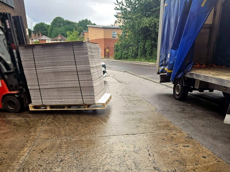 Forklift loading palletised goods into a blue curtain-side van